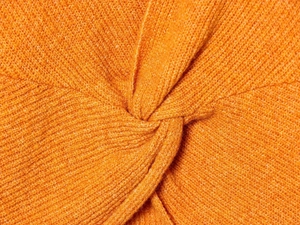 Detail of orange knitted sweater featuring a stylish back knot design and fine stitch texture