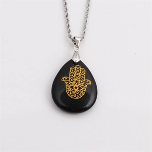 Detail of black teardrop pendant with golden Hamsa Hand on a silver rope chain