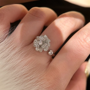 Detail shot of a silver zircon flower open ring on a hand with soft white fur background