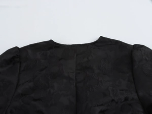 Detailansicht aus schwarzem Jacquard-Stoff mit floraler Textur und Puffärmel-Design