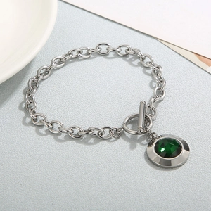Détail d'un bracelet en chaîne argentée avec pendentif gemme verte et un fermoir à bascule