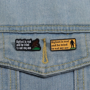 Detail of Bigfoot enamel pins on denim jacket showing funny text and metal craftsmanship
