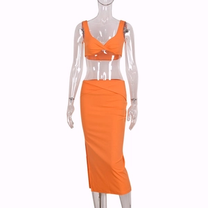 Detail of bright orange two-piece set featuring V-neck twist crop top and high waist skirt