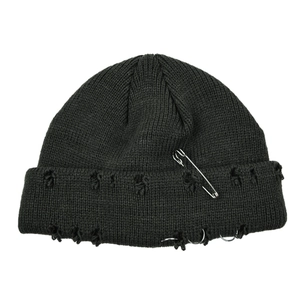 Detail of punk style distressed black knit beanie with silver safety pin and ring accents