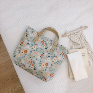 Detail of floral canvas tote bag featuring leather handles and secure metal rivets