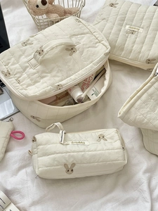 Cream quilted rabbit embroidery cosmetic bag set on soft white fabric background