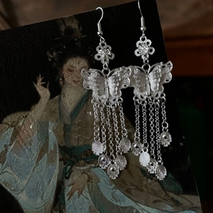 Detailed close-up of silver hollow butterfly tassel earrings with metal drop pendants
