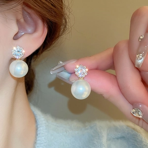 Detailed view of silver needle flower earrings with crystals and round white pearls