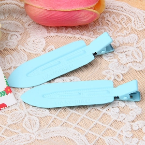 Close-up of light blue metal paint hair clips with UANODIAM lettering on lace fabric