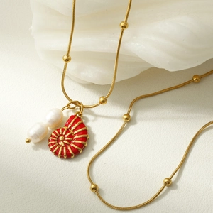 Detail of red enamel nautilus and double pearl pendant on golden snake chain