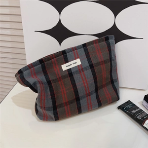 Detail view of red plaid cotton makeup bag featuring the simple wish woven label