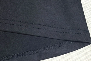 Détail de la couture à double aiguille et de l'ourlet sur une robe en maille noire