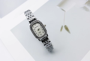 Macro detail of silver oval women's watch with rhinestone bezel and metal chain band