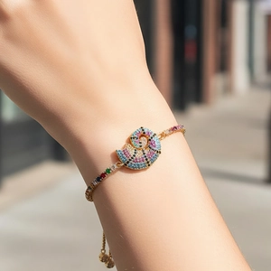 Adjustable gold bracelet with a shell charm featuring colorful zircon stones
