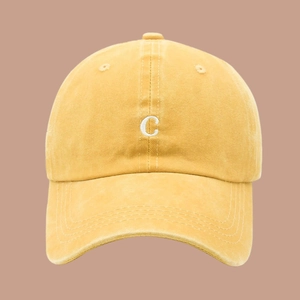 Detail shot of the 3D embroidered white letter C on a mustard yellow washed cotton cap