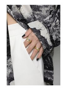 Close-up of golden irregular textured rings with blue and white zircons on a model