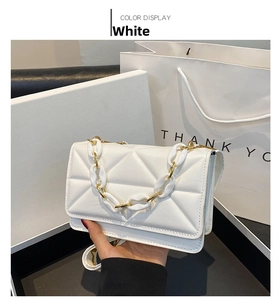 Detail view of white quilted cross body bag with chain strap and embossed texture