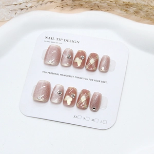 Pink cat eye press-on nails with golden butterfly and rhinestones on a white display card