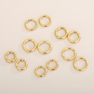Vue à plat de boucles d'oreilles clips en acier inoxydable doré sur fond crème