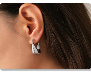 Close-up of minimalist silver geometric earring on ear showing polished thick hoop design