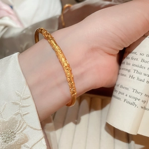 Close-up of gold-plated bangle featuring intricate embossed floral patterns and craftsmanship