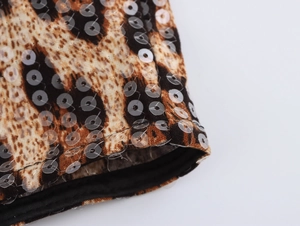 Détail du tissu léopard avec paillettes brillantes sur le bord de la manche et coutures