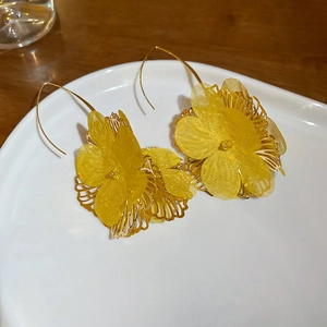 Detail of yellow flower drop earrings with sheer fabric petals on white ceramic plate