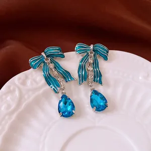 Elegant vintage bow dangle earrings with blue stones on white ceramic tray
