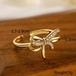 Macro shot of gold bow ring with zircon inlay showing size specs on dark wood