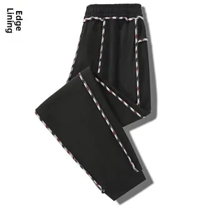 Detail of black sports trousers showing piped inner lining and plaid pattern binding