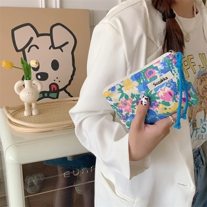 Close-up of model holding the colorful floral canvas makeup bag in a home setting