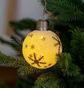 Detail of warm glowing snowflake Christmas ball ornament hanging with rustic hemp rope