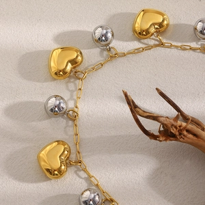 Détails de breloques cœur en or 18 carats et perles argentées sur une chaîne à maillons