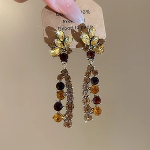 Detailed macro of crystal tassel earrings with amber rhinestones held by hand