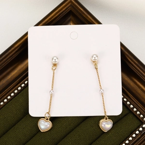 French vintage gold pearl earrings with long tassels and heart pendants on green velvet