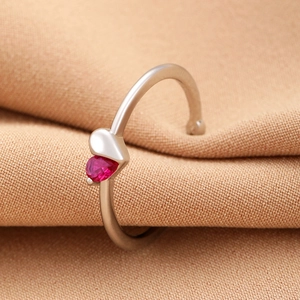 Detail of silver heart ring with red heart gemstone nestled in soft brown fabric