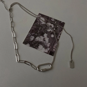 Détail du collier géométrique argenté avec chaîne trombone et pendentif mousqueton