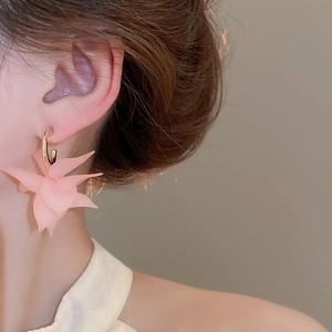 Detail of pink acrylic petal earrings with gold metal loops on a female model