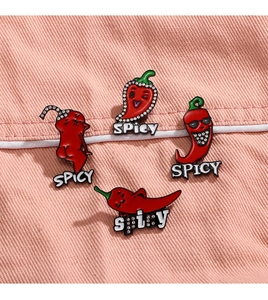 Detailed view of 4 red chili enamel pins with funny faces on pink denim background