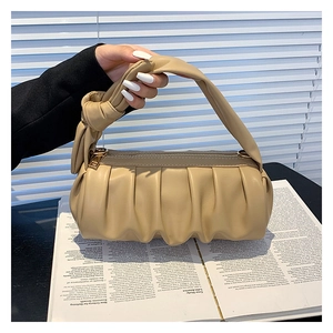 Detailed shot of pleated khaki cloud bag with knotted handle and golden zipper hardware