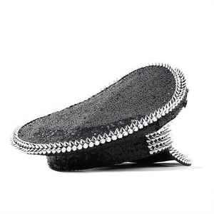 Detail of black sequined military hat featuring silver metal spikes on a white background