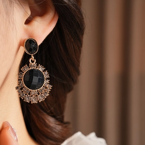 Gros plan de boucles d'oreilles vintage avec cristaux noirs et finition dorée sur modèle