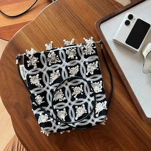Detailed macro view of white floral embroidery and tassel fringe on black canvas bag