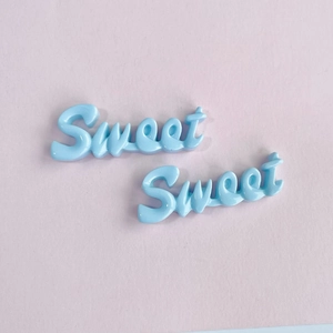 Détail de breloques Sweet en résine bleue pour bricolage sur un fond rose clair