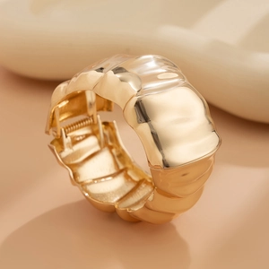 Macro detail of polished gold wave bangle with visible mechanical hinge closure