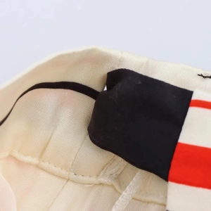 Detailed close-up showing satin fabric texture and red striped stitching on the skirt