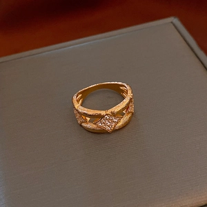 Close-up of golden vintage ring with rhombus zircon inlay and tree bark texture