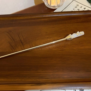 Detailed view of lily of the valley hair pin with golden leaves and white petals