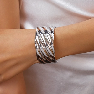 Close-up of chunky silver wavy textured open cuff bracelet worn on model's wrist