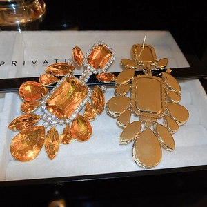 Detailed close-up of statement earrings with orange gemstones and sparkling crystals